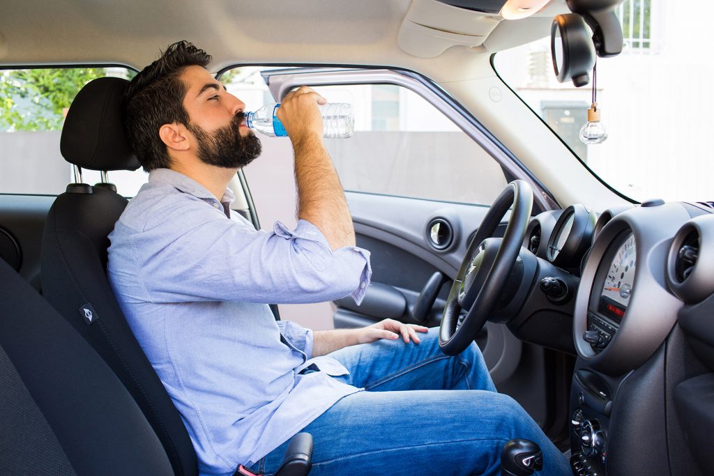 Personas sostiene una botella de agua en el interior de un coche