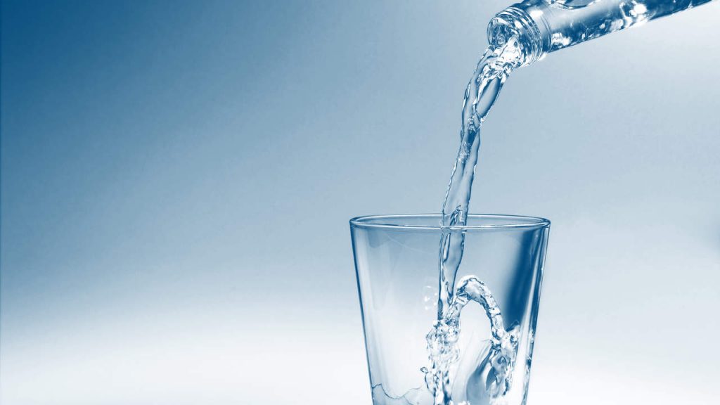 servir agua en una vaso desde una botella de agua